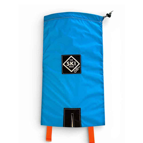A bright blue 2026 Ski Pack with Orange Straps with a black 'The Ski Pack' logo patch in the center and orange drawcord straps at the bottom, shown on a plain white background.