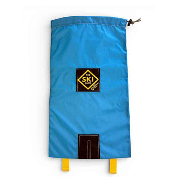 A bright blue drawstring Ski bag with a black and yellow 'The Ski Pack' logo patch on the front, featuring a top drawstring closure and yellow loops at the bottom, shown against a plain white background.