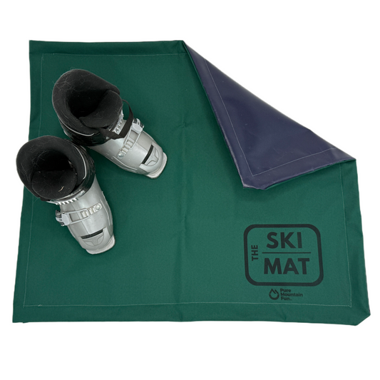Green ski mat with ski boots on a white background