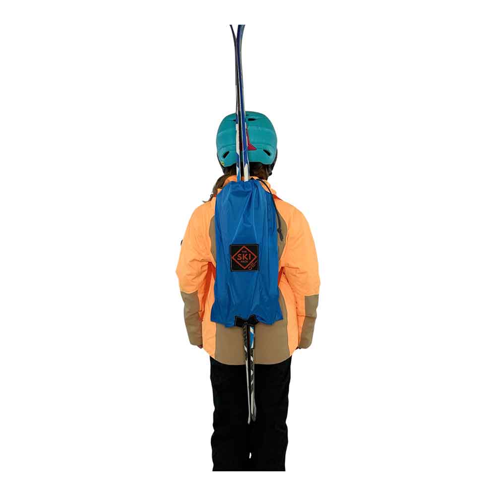 A kid shown from behind wearing a bright blue ski backpack with a black diamond logo patch, an orange jacket, black pants, and a teal helmet, with skis visible against a plain white background.